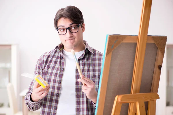 Young male artist drawing pictures in bright studio