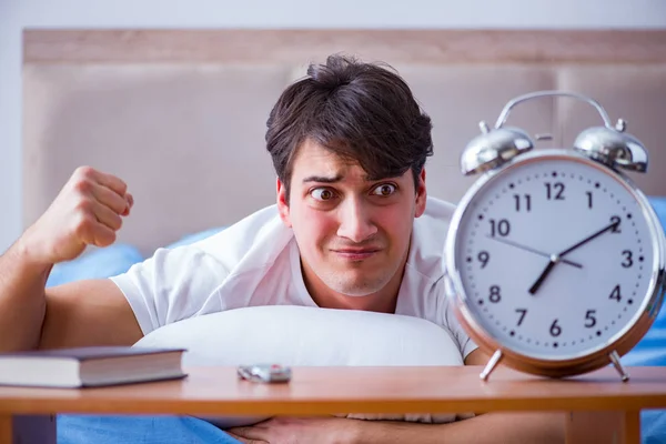 Hombre en la cama frustrado sufriendo de insomnio con un zueco de alarma — Foto de Stock