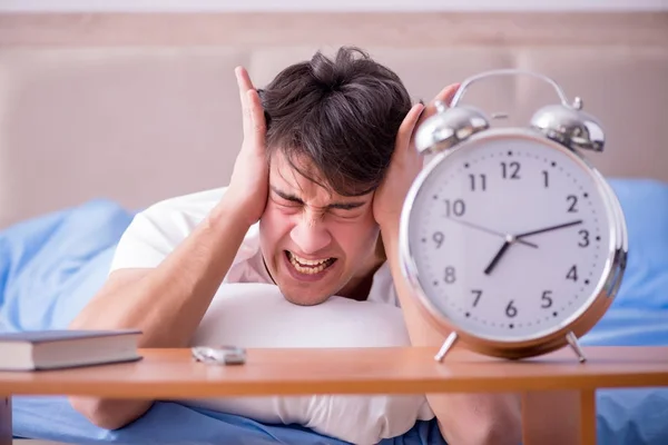 Uomo a letto frustrato soffre di insonnia con un blocco di allarme — Foto Stock