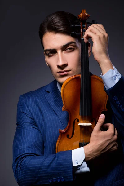 Young man playing violin in dark room — Stock Photo, Image