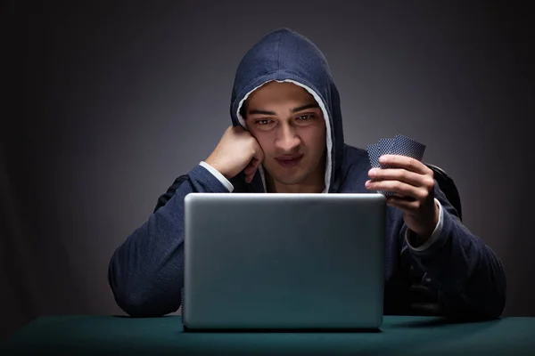 Joven con una sudadera con capucha sentado frente a una computadora portátil —  Fotos de Stock