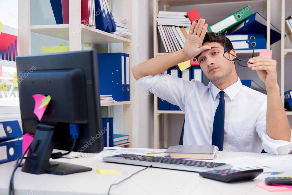 Businessman working in the office with piles of books and papers