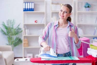 Mutlu ev hanımı evde ütü yapıyor.