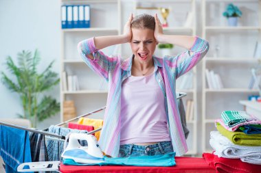 Üzücü kadın evde kıyafetleri ütülüyor.