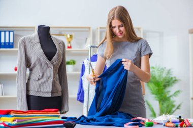 Atölyede çalışan genç bayan terzi yeni elbise üzerinde çalışıyor.