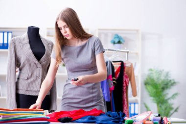 Atölyede çalışan genç bayan terzi yeni elbise üzerinde çalışıyor.