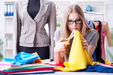 Atölyede çalışan genç bayan terzi yeni elbise üzerinde çalışıyor.