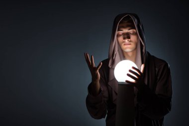 Karanlık odada kristal küreli genç büyücü