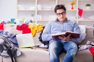 Genç adam dağınık bir odada çalışıyor.