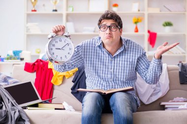 Genç adam dağınık bir odada çalışıyor.