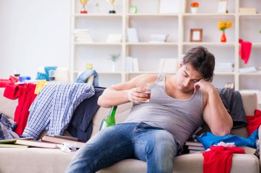 Dağınık bir odada alkol alan genç bir öğrenci.