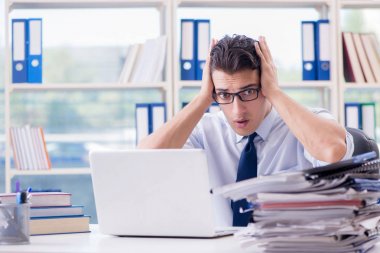 Ofiste çalışan aşırı çalışma evrakları olan bir iş adamı.