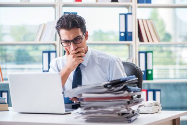 Ofiste çalışan aşırı çalışma evrakları olan bir iş adamı.
