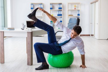 Genç işadamı iş yerinde spor yapıyor.