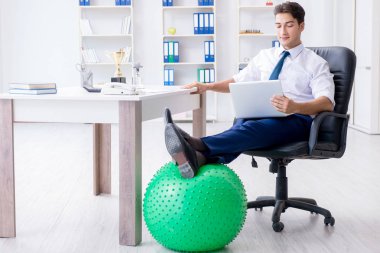 Genç işadamı iş yerinde spor yapıyor.