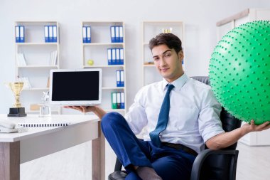 Genç işadamı iş yerinde spor yapıyor.