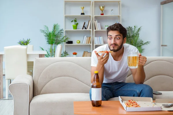 Pizza yiyen adam evde yemek yiyor, dinleniyor.
