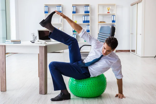 Young businessman doing sports stretching at workplace — Stock Photo, Image