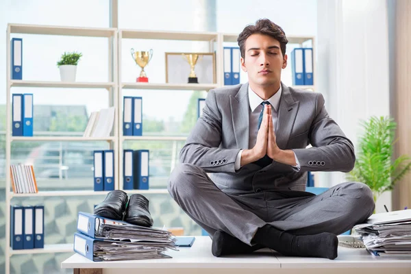 Businessman sitting on top of desk in office — Stock Photo, Image