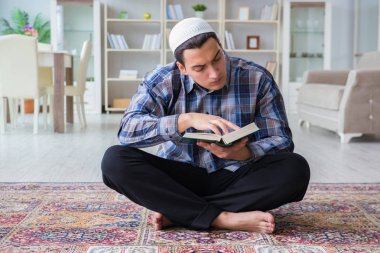 Genç Müslüman adam evde dua ediyor.