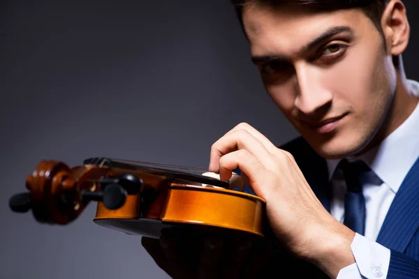 Young man playing violin in dark room — Stock Photo, Image