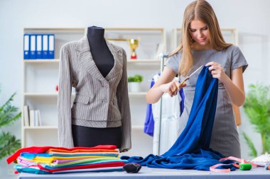 Atölyede çalışan genç bayan terzi yeni elbise üzerinde çalışıyor.