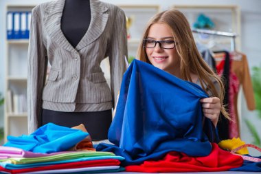 Atölyede çalışan genç bayan terzi yeni elbise üzerinde çalışıyor.