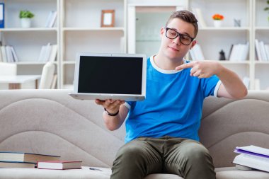 Sınavlara hazırlanan genç öğrenci kanepede ders çalışıyor.