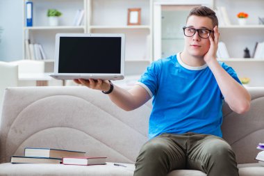 Sınavlara hazırlanan genç öğrenci kanepede ders çalışıyor.