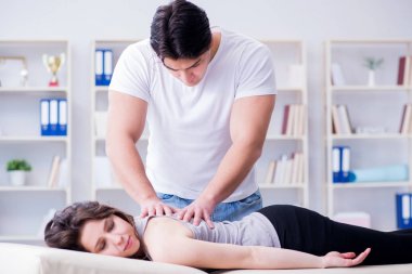 Genç doktor kayropraktik uzmanı kadın hastaya masaj yapıyor.