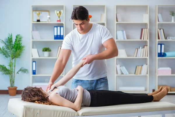 Genç doktor kayropraktik uzmanı kadın hastaya masaj yapıyor.