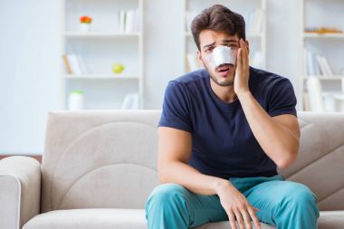 Genç adam estetik cerrahi burnundan sonra evde iyileşiyor.