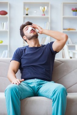 Genç adam estetik cerrahi burnundan sonra evde iyileşiyor.