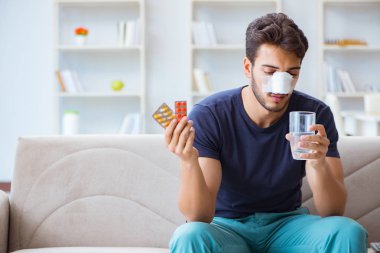 Genç adam estetik cerrahi burnundan sonra evde iyileşiyor.