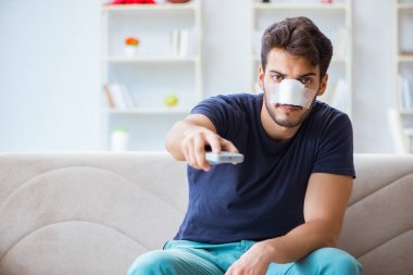 Genç adam estetik cerrahi burnundan sonra evde iyileşiyor.