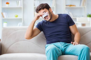 Genç adam estetik cerrahi burnundan sonra evde iyileşiyor.