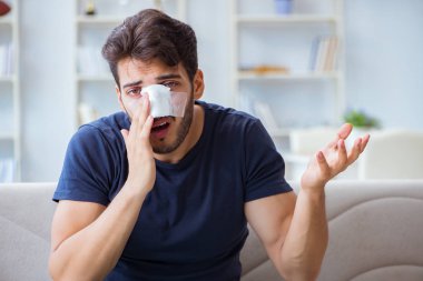 Genç adam estetik cerrahi burnundan sonra evde iyileşiyor.