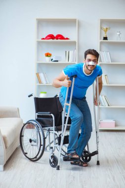 Genç adam ameliyattan sonra koltuk değnekleriyle evde iyileşiyor.