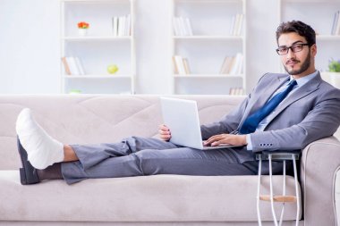 Koltuk değneği ve kırık bacağı olan bir iş adamı.