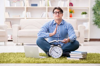 Genç yakışıklı adam evde yerde oturuyor.