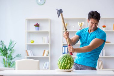 Evde karpuz yiyen bir adam.