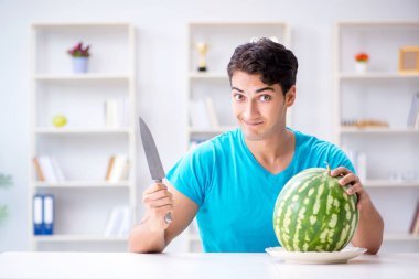 Evde karpuz yiyen bir adam.