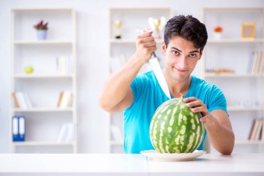 Evde karpuz yiyen bir adam.