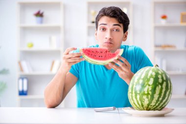 Evde karpuz yiyen bir adam.
