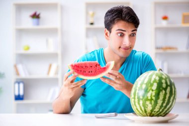 Evde karpuz yiyen bir adam.