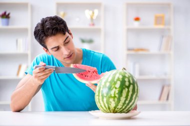 Evde karpuz yiyen bir adam.