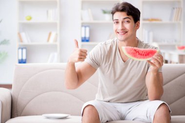 Evde karpuz yiyen bir adam.