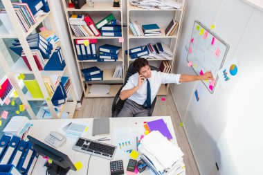 Ofiste kitap ve kağıtlarla çalışan bir işadamı.