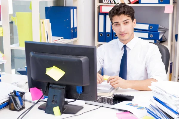 Zakenman werkzaam in het kantoor met stapels boeken en papieren — Stockfoto