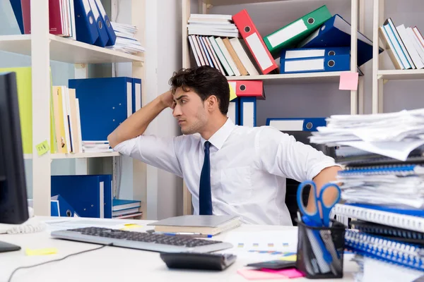 Uomo d'affari che lavora in ufficio con mucchi di libri e carte — Foto Stock